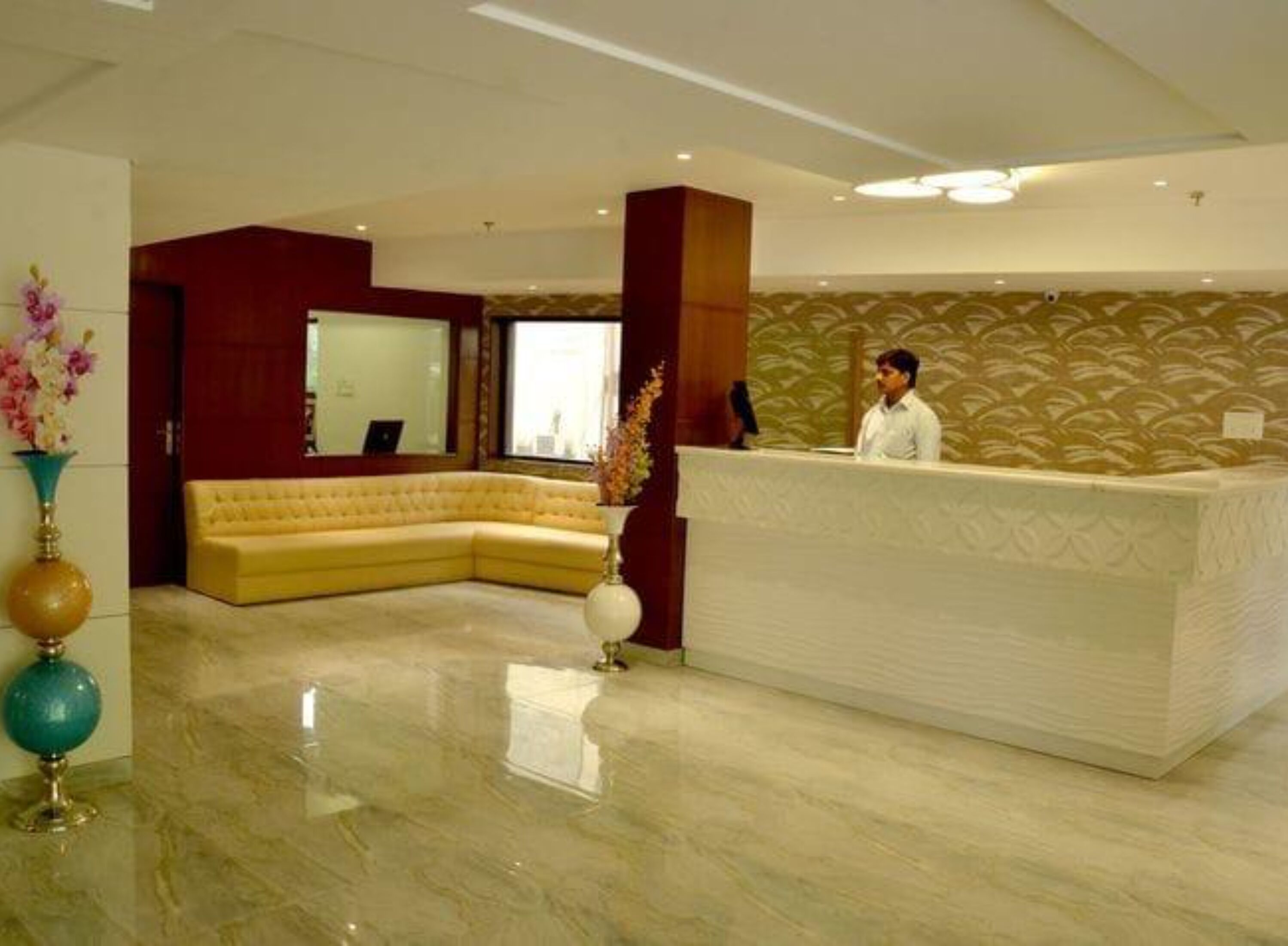 A reception area with a curved yellow sofa, a white reception desk, and a large window.