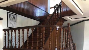 A wooden staircase with a curved landing, a white chair, and two potted plants. - House with private pool and extensive garden (Lapu-Lapu City,)
