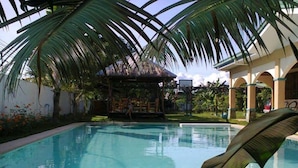 A swimming pool with palm trees, a covered seating area, and a building with arches. - House with private pool and extensive garden (Lapu-Lapu City,)