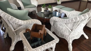 A room with white wicker furniture, including chairs and a table, with green cushions. There are potted plants on the table. - House with private pool and extensive garden (Lapu-Lapu City,)