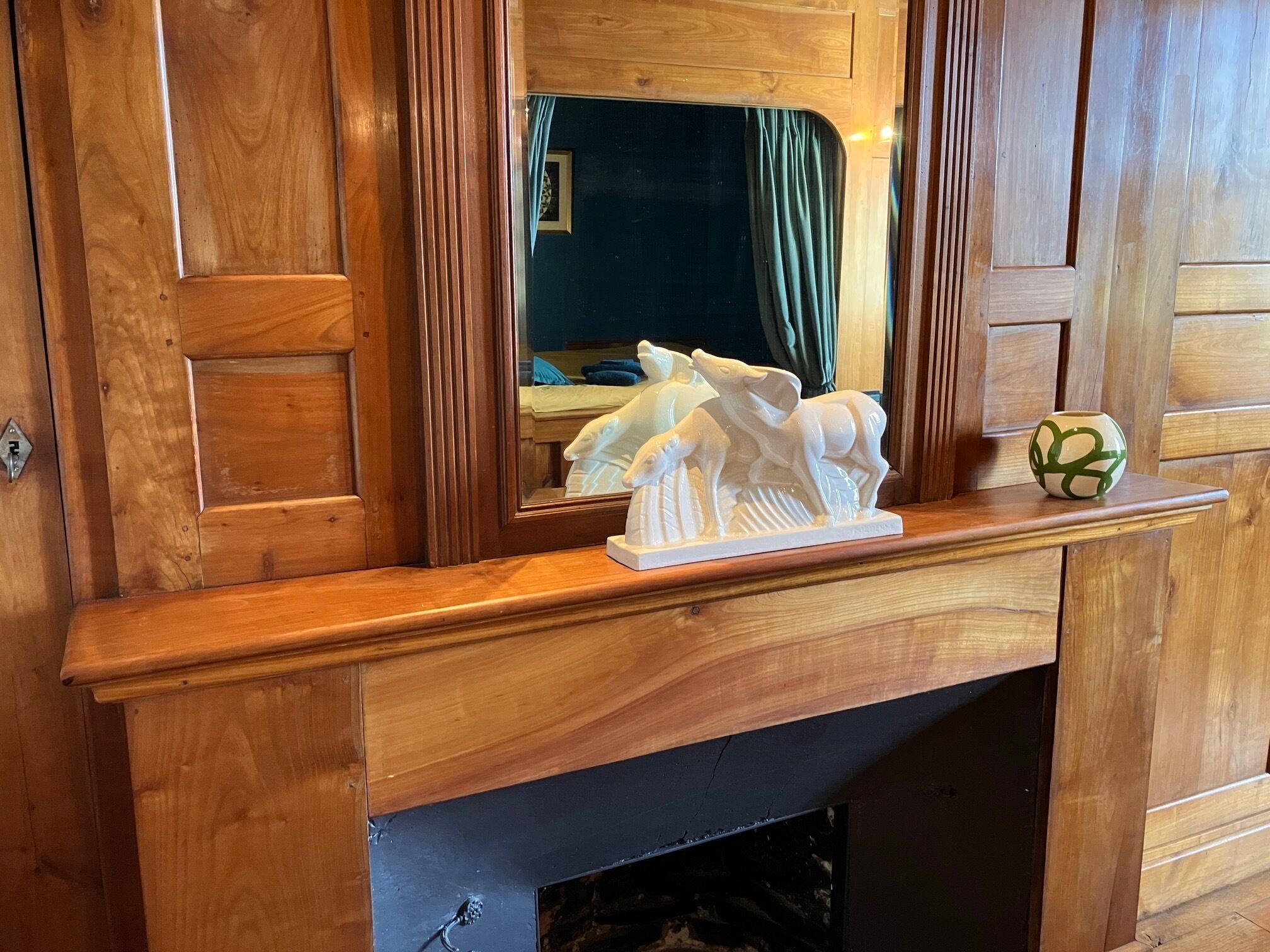 A wooden mantelpiece with a sculpture and a decorative bowl.