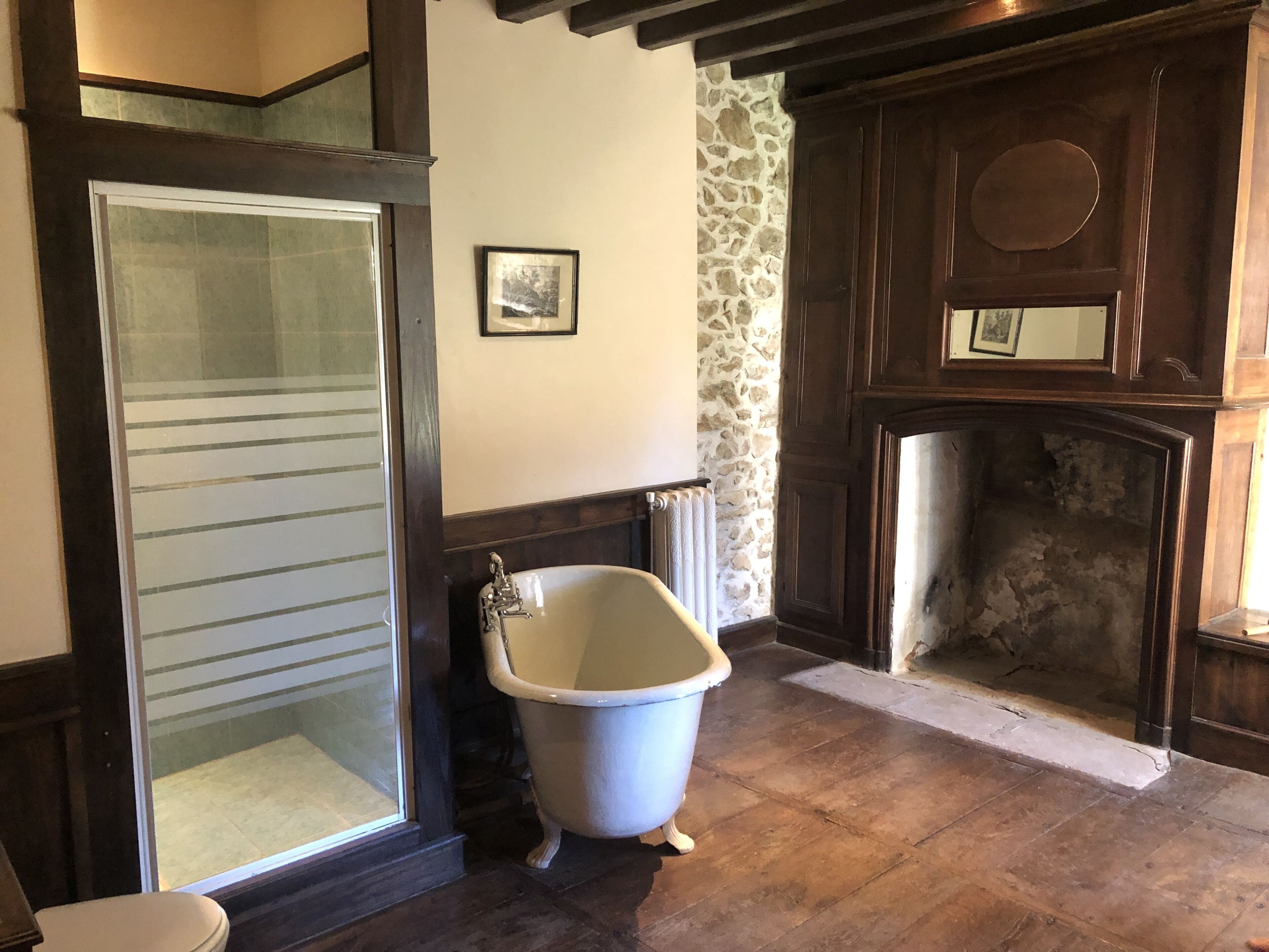 Un baño con bañera, inodoro, pared de piedra y chimenea.