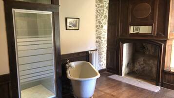 Un baño con bañera, inodoro, pared de piedra y chimenea.