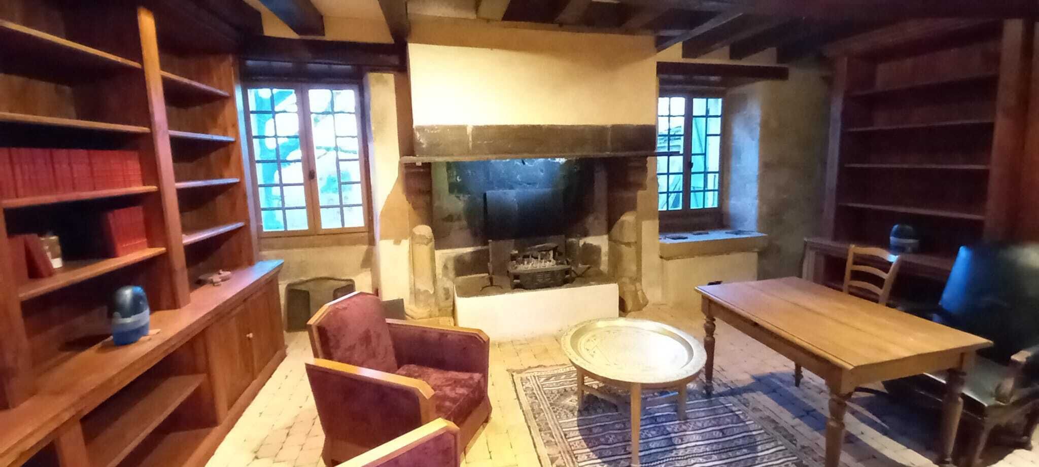 A cozy room with a fireplace, wooden furniture, and bookshelves.