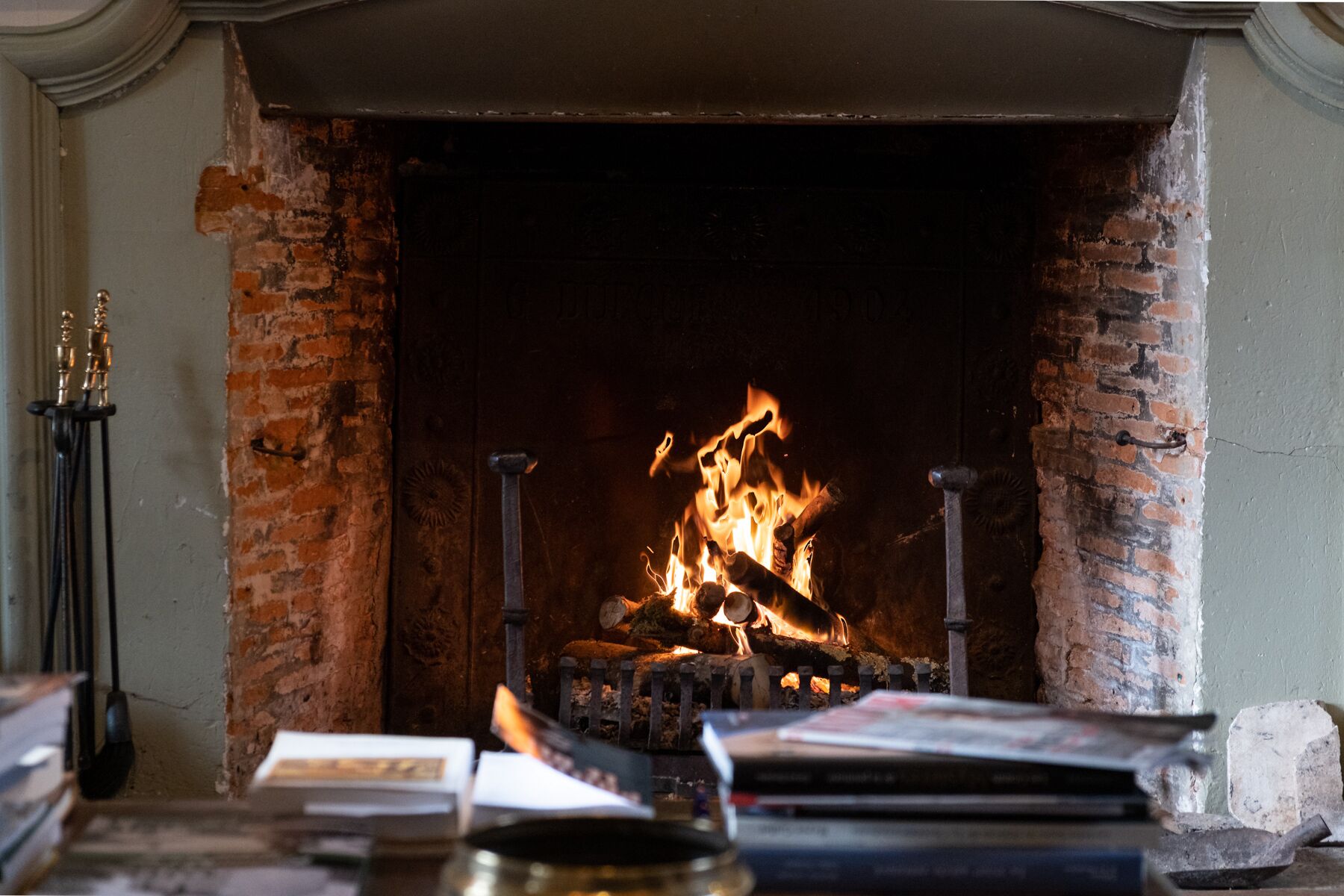 A fireplace with a fire, surrounded by books and a candle holder.