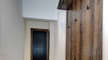 Un pasillo con una puerta de madera oscura, un llamativo panel de madera y suelo alfombrado.
