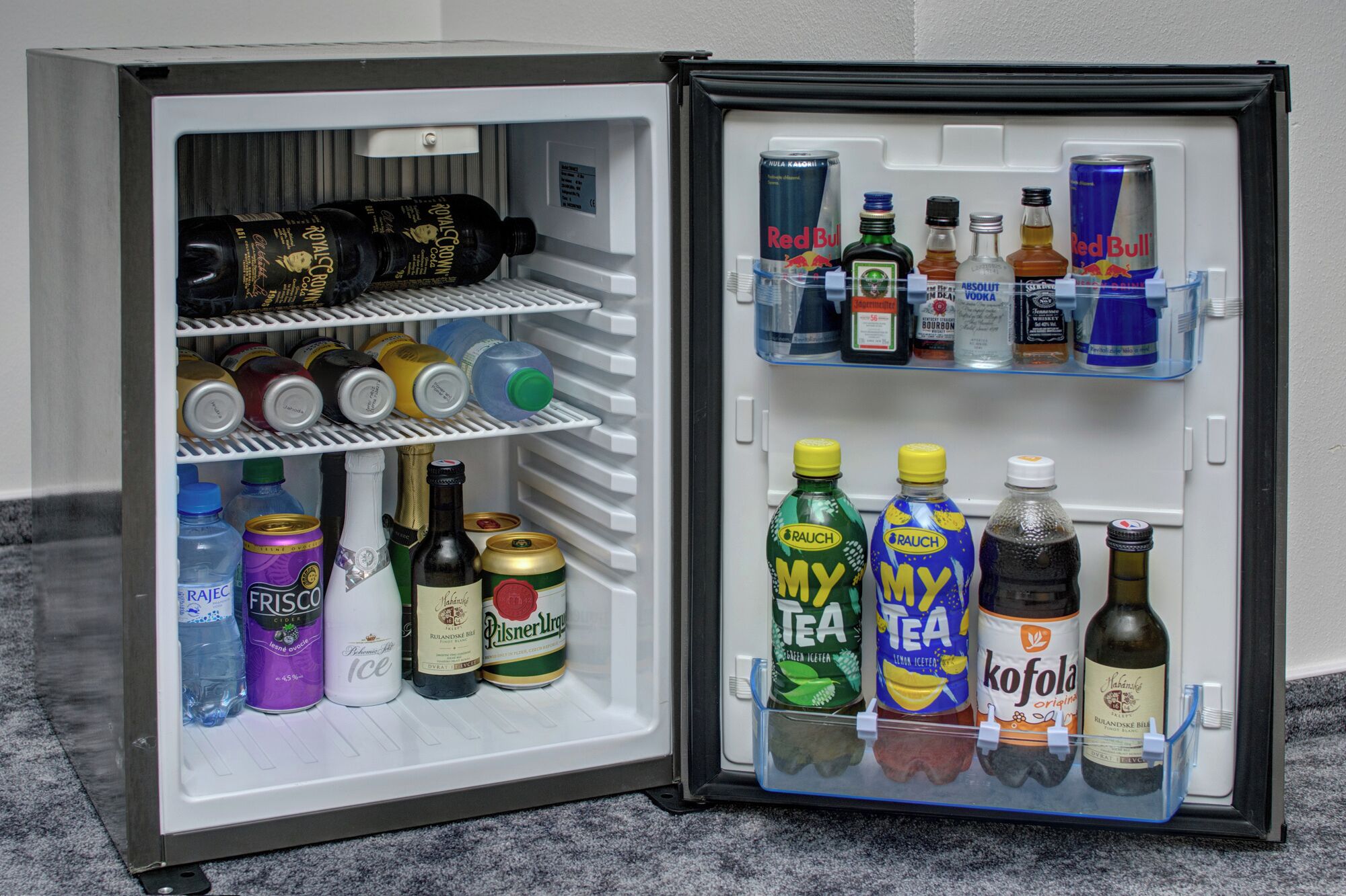 An open mini-fridge with various beverages including sodas, beers, and spirits.