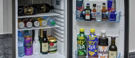 An open mini-fridge with various beverages including sodas, beers, and spirits.