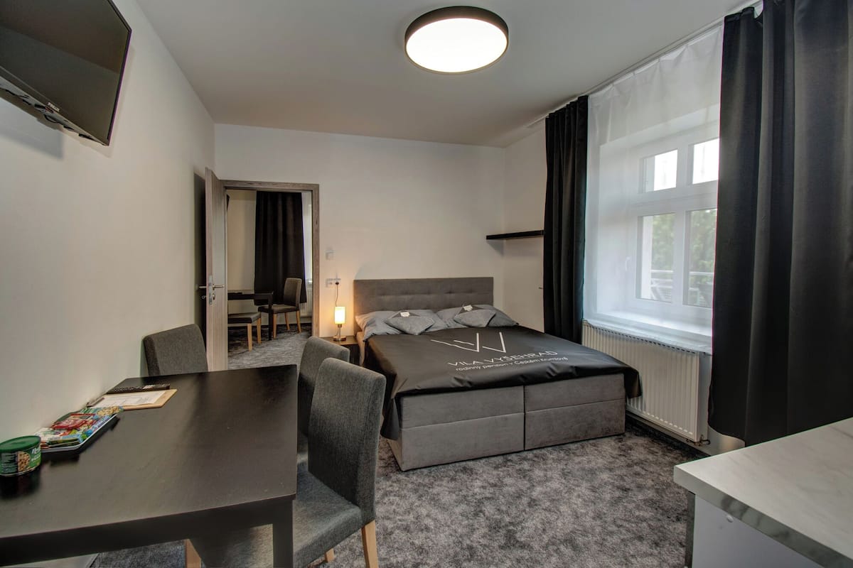 Een hotelkamer met een bed, een bureau, een stoel, een televisie en een raam met gordijnen.