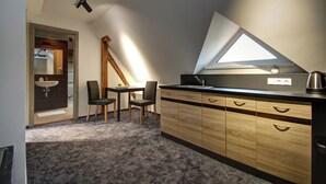 Une cuisine compacte avec un meuble en bois, un plan de travail noir et un puits de lumière.