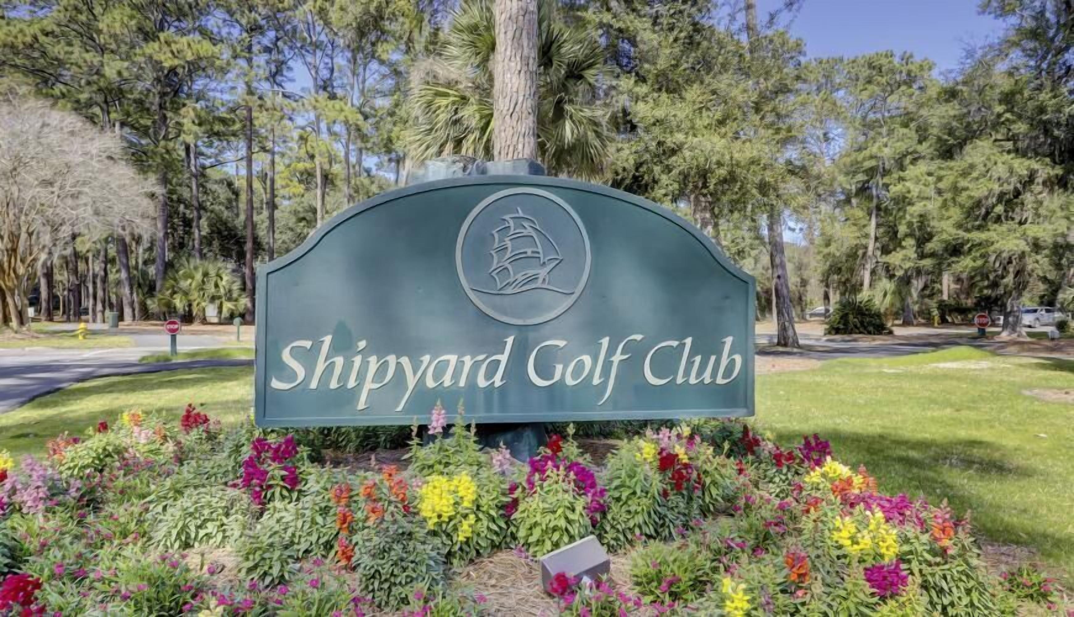 A sign for Shipyard Golf Club surrounded by colorful flowers.