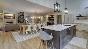 Een moderne keuken met een centraal eiland, barkrukken en hanglampen.