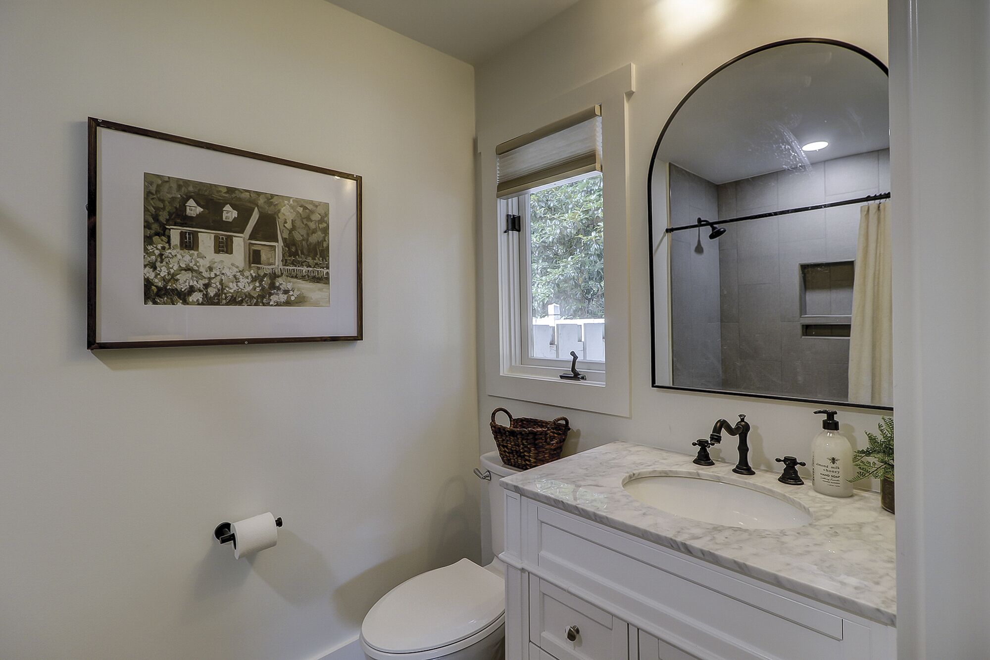 A bathroom with a toilet, sink, and a framed picture on the wall.