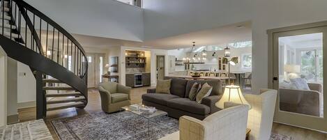 A spacious living room with a staircase, a dining area, and a kitchen.
