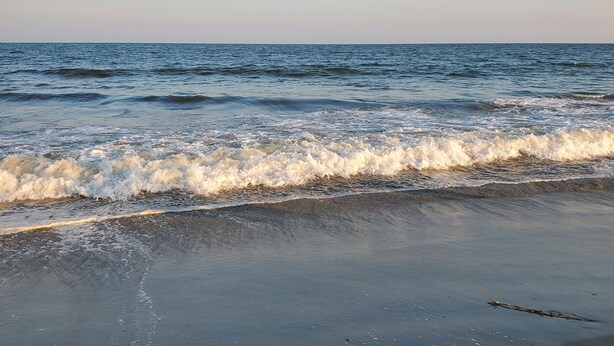 A beach with waves gently lapping onto the shore. - Family Beach House - Pet-friendly - private heatable pool, close to the beach (Isle of Palms)