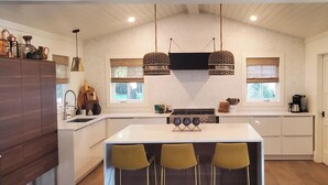 A modern kitchen with a central island, pendant lights, and a stainless steel refrigerator. - Family Beach House - Pet-friendly - private heatable pool, close to the beach (Isle of Palms)