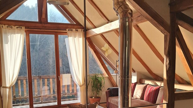 Un dormitorio acogedor en el ático con un ventanal grande, un balcón y vistas al exterior.