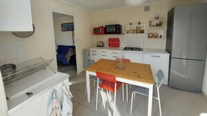 Eine kleine Küche mit weißen Schränken, einem Holztisch und einem Kühlschrank.