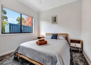 Relax in this serene bedroom with a large bed, nightstand, and stunning view of the surrounding landscape.