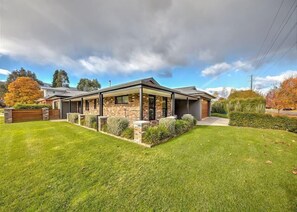 Stunning two-story home with a beautifully manicured lawn and mature trees.