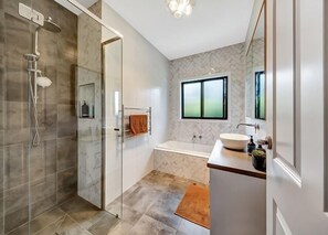 Bathroom features a glass-enclosed shower, bathtub, and vanity with sink and mirror.