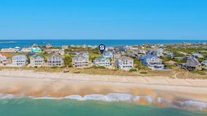 A coastal residential area with beachfront properties, a clear sky, and a calm sea. - Premier Oceanfront w/ Private Pool, Hot Tub, Game Room, Putting Green, Theater (Hatteras)