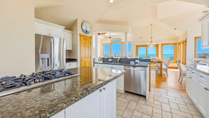 A spacious kitchen with granite countertops, stainless steel appliances, and large windows offering ocean views. - Premier Oceanfront w/ Private Pool, Hot Tub, Game Room, Putting Green, Theater (Hatteras)