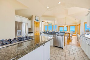 A spacious kitchen with granite countertops, stainless steel appliances, and large windows offering ocean views.
