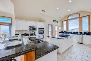 Enjoy cooking with a view from the kitchen's large island, featuring a sink and ocean views through large windows.