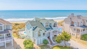A coastal house with a large deck, a swimming pool, and a view of the ocean. - Premier Oceanfront w/ Private Pool, Hot Tub, Game Room, Putting Green, Theater (Hatteras)