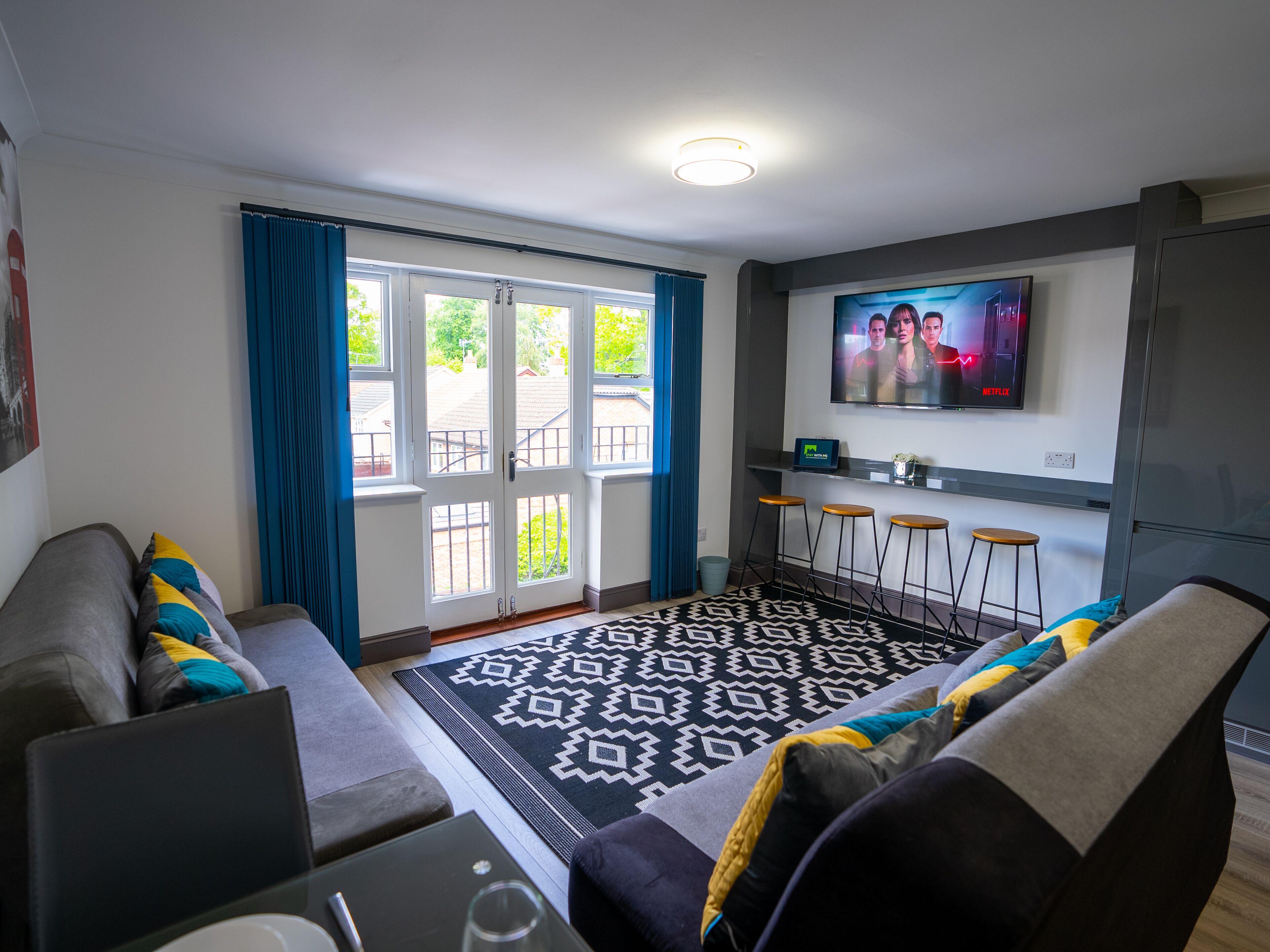 Relax on the plush sofa adorned with modern throw pillows, adding a pop of color and texture to the room. The flat-screen TV provides entertainment at your fingertips, perfect for movie nights or catching up on your favorite shows.