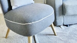 Un soggiorno moderno con una poltrona grigia, una lampada da terra e un divano grigio con cuscini decorati.