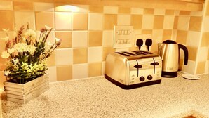 Una cucina con un piano di lavoro in granito, un tostapane, un bollitore e un vaso con fiori.