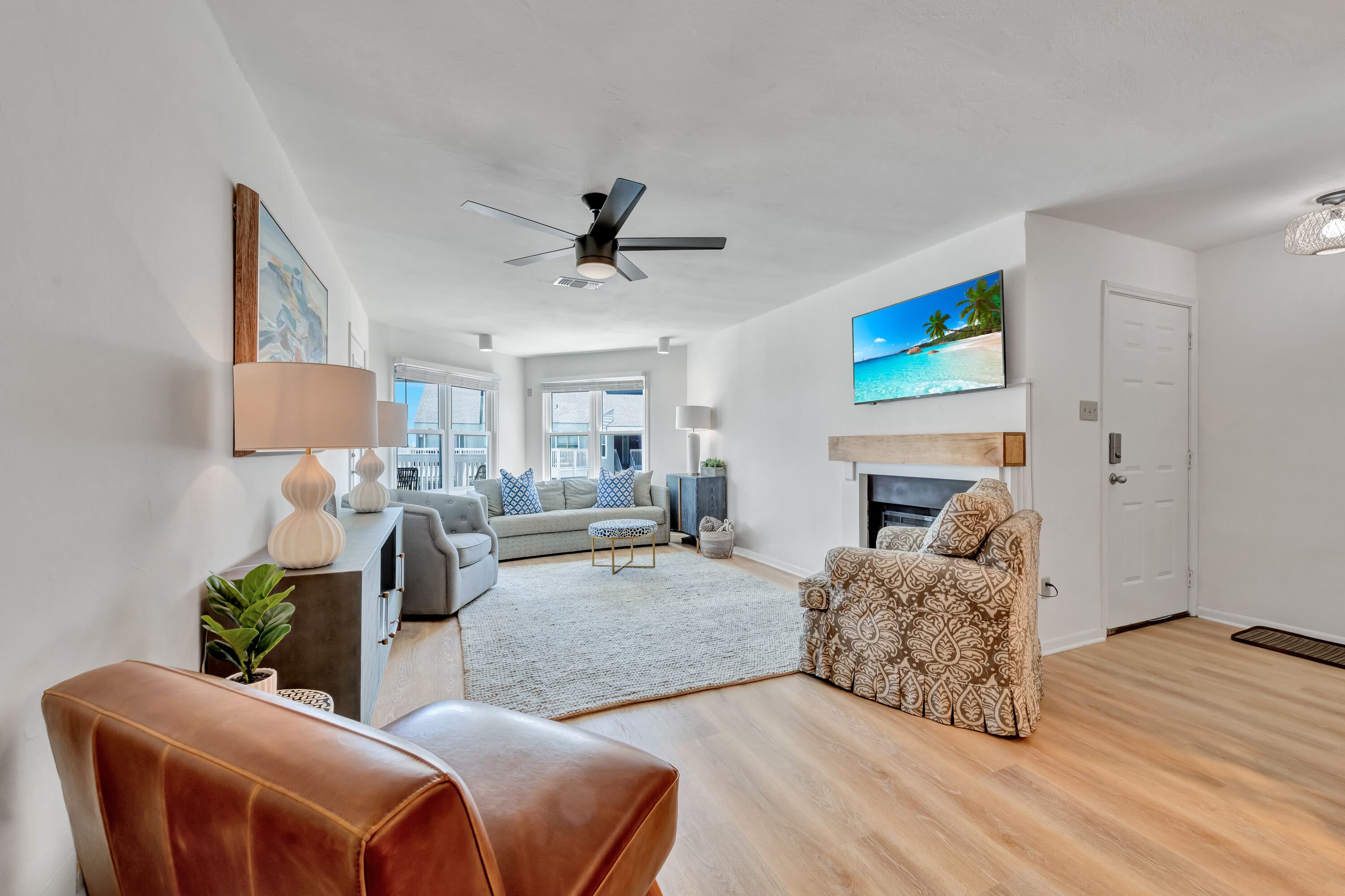 A modern living room with a sofa, armchair, and a fireplace.