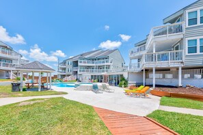 A residential building with multiple balconies, a swimming pool, and outdoor seating areas.