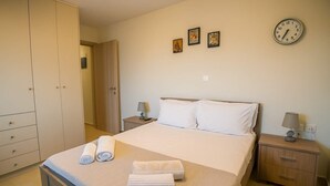 Een hotelkamer met een bed, twee nachtkastjes, een kledingkast en een wandklok.