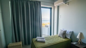 A hotel room with a bed, a nightstand, a lamp, and a view of the sea through a window.