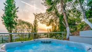 A hot tub with a view of the sunset and surrounding trees.