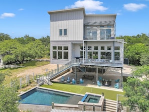 A two-story building with a pool, outdoor seating, and a covered deck area.