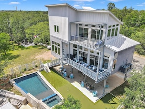 A multi-story house with a pool, outdoor seating, and a covered patio.