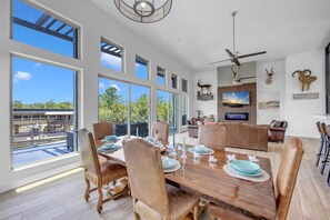A spacious dining area with a large wooden table, multiple chairs, and a view of the outdoors.