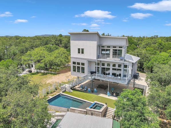 A multi-story building with a pool, outdoor seating, and a view of the surrounding forest.