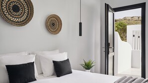 Een moderne slaapkamer met een bed, kussens, een hanglamp, een wanddecoratie van geweven materiaal en uitzicht op een buitenruimte.