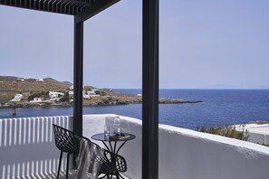 Un balcone con un tavolo, due sedie e vista sul mare e sugli edifici in lontananza.