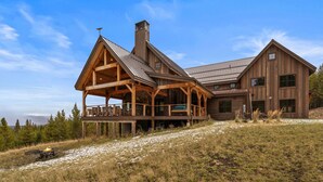 Eine große Holzhütte mit überdachter Veranda und einem Blechdach, eingebettet in eine verschneite Landschaft.