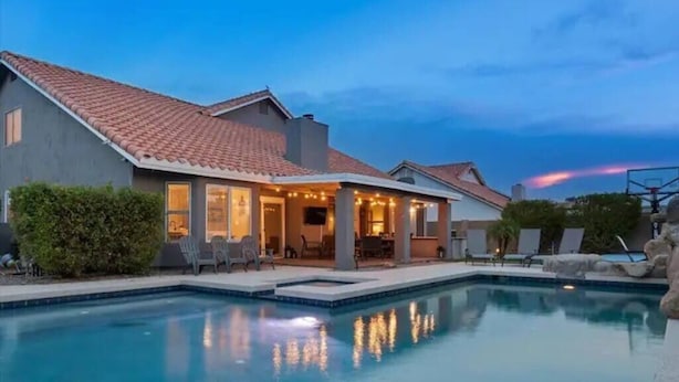 A two-story house with a swimming pool, outdoor seating, and a well-lit patio area. - Modern Majestic Home with Pool, Spa & Basketball (Mesa)