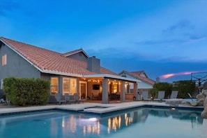 Une maison à deux étages avec une piscine, un espace extérieur aménagé pour se détendre et une terrasse bien éclairée.