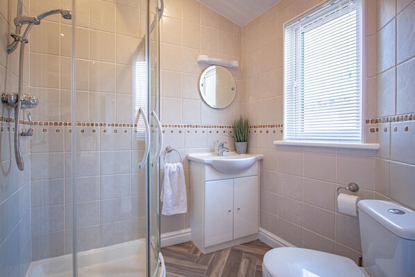 A bathroom with a shower, toilet, sink, and a mirror. - Betteridge View Lodge - a holiday lodge that sleeps 6 guests in 3 bedrooms (Windermere)
