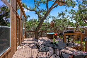 Una terraza de madera con mesa, sillas, una parrilla y un jacuzzi.