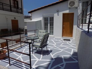 A patio with a table and chairs, a wooden door, and a white building with a geometric patterned floor. - VS studios Standard Double Room (Skiathos)